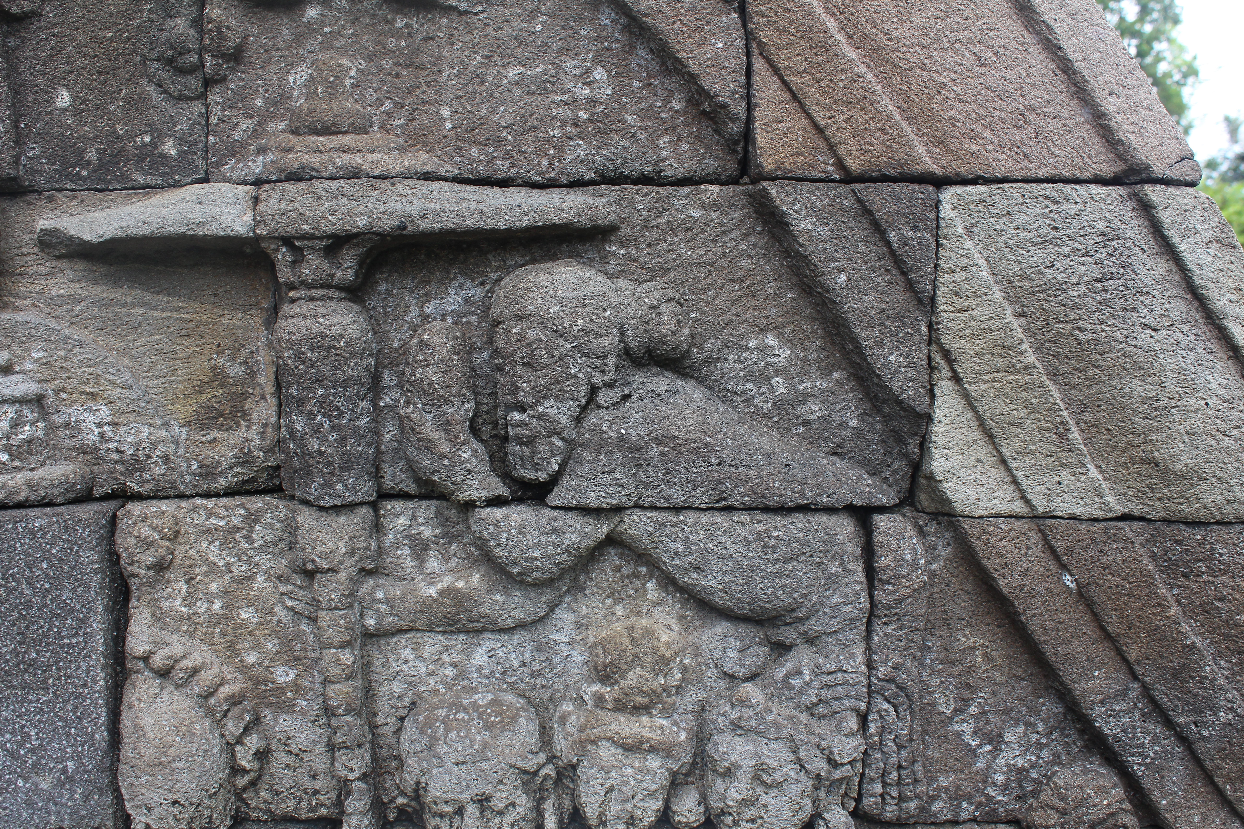 Relief carving showing a man bowing towards a parasol