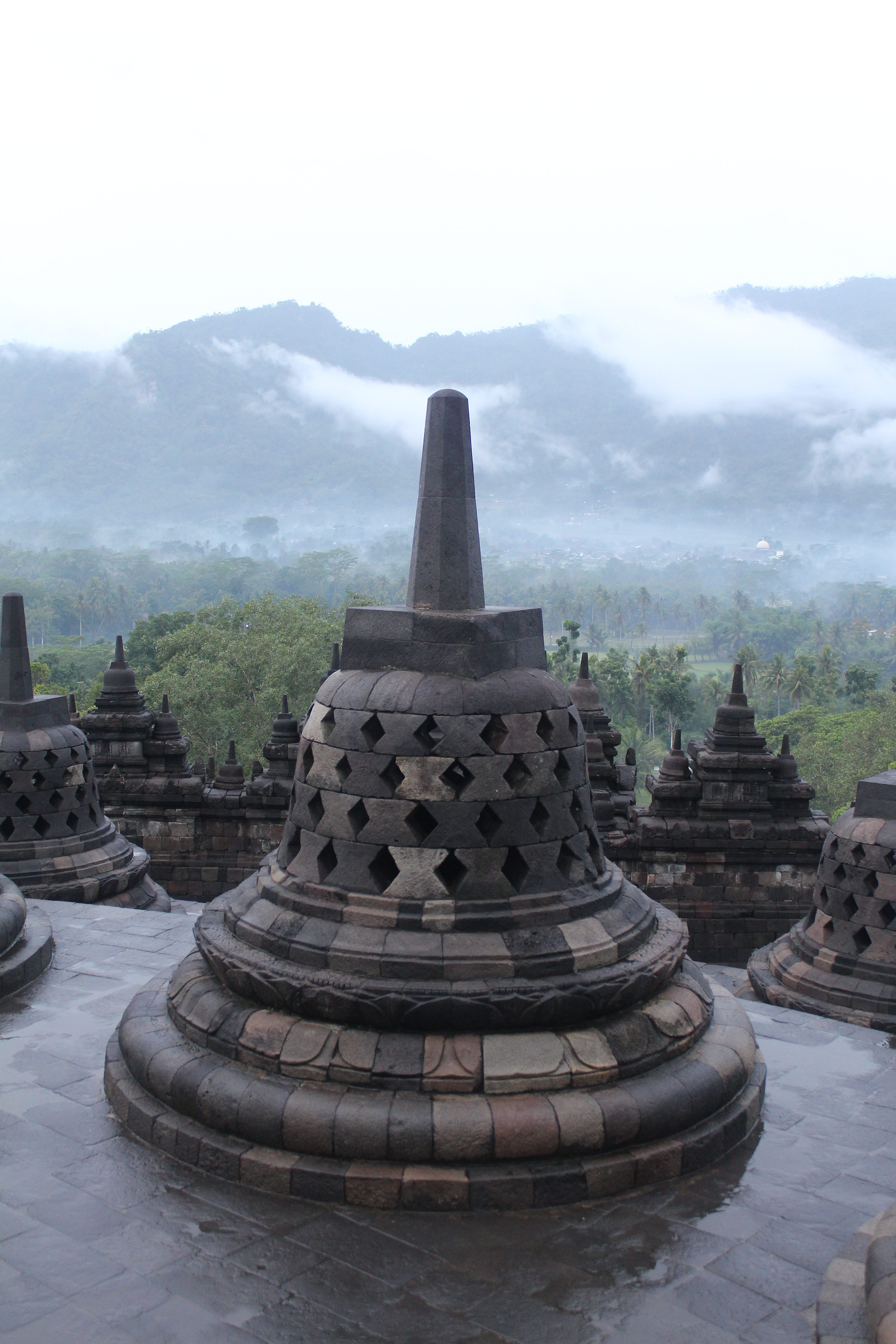 Series of stone stupas high above a lush landscape