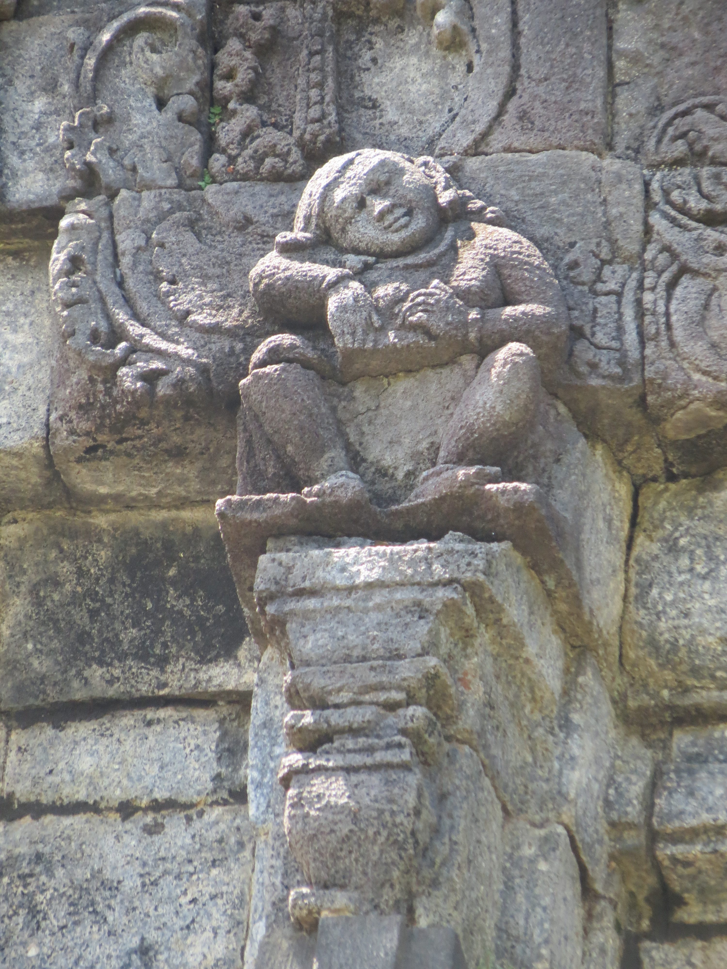 Temple wall sculpture of seated figure leaning on elbow