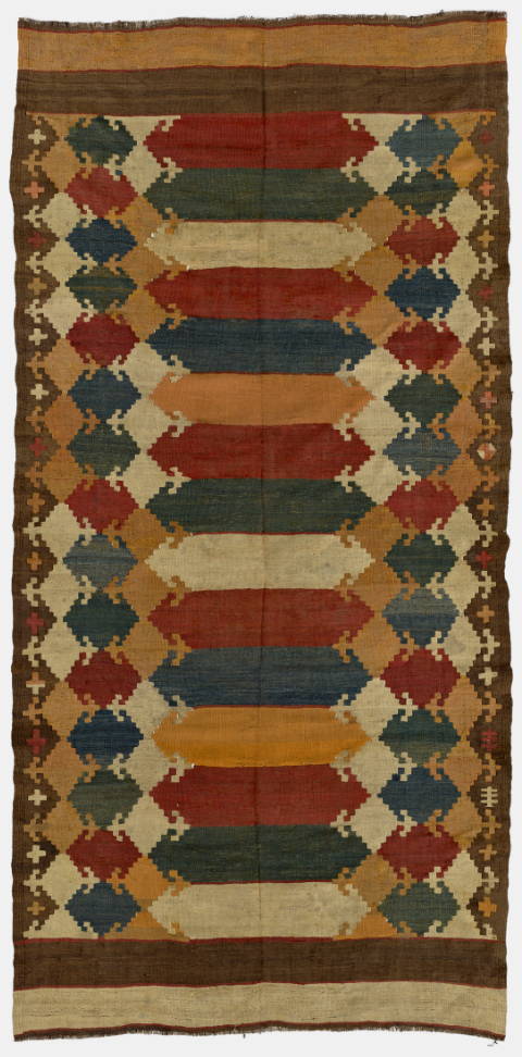 A woven kilim featuring geometric shapes in intense red, orange, dark blue, dark green, white, and black