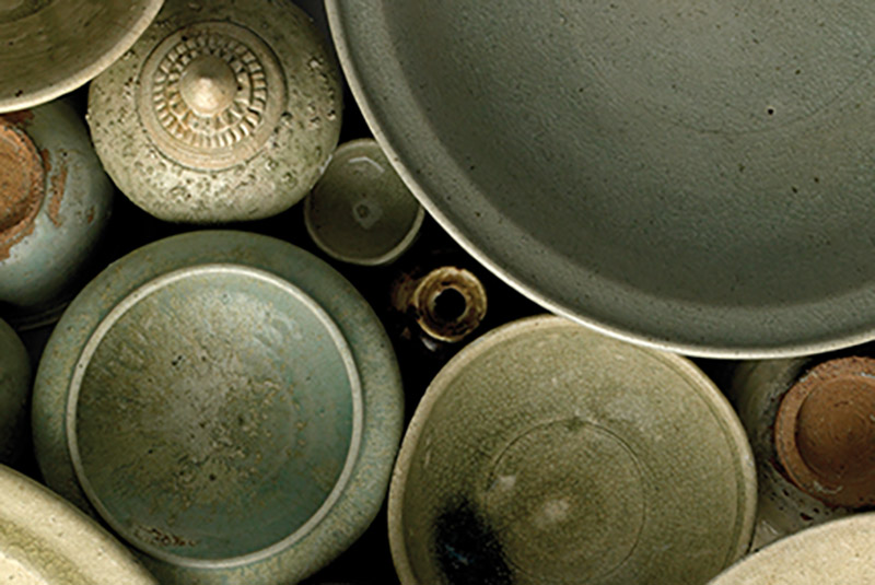 an array of pottery in pale greens and browns, seen from above.