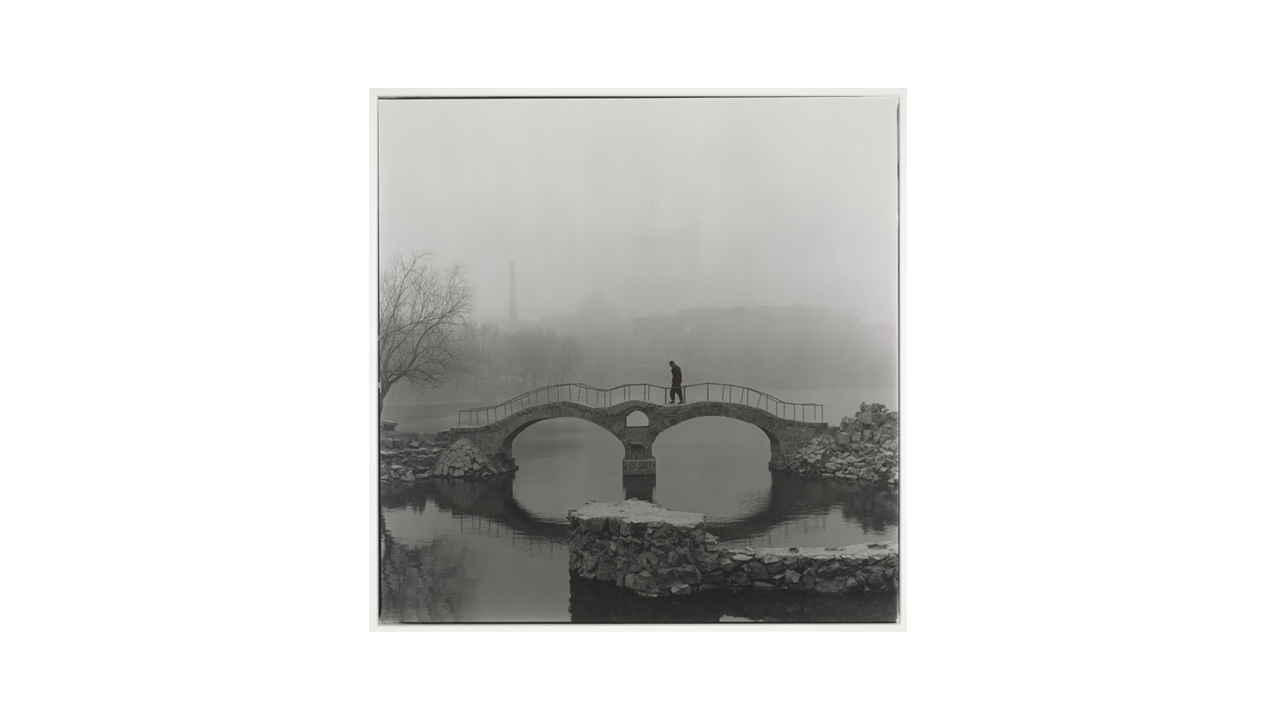 photo of man walking over a bridge in fog